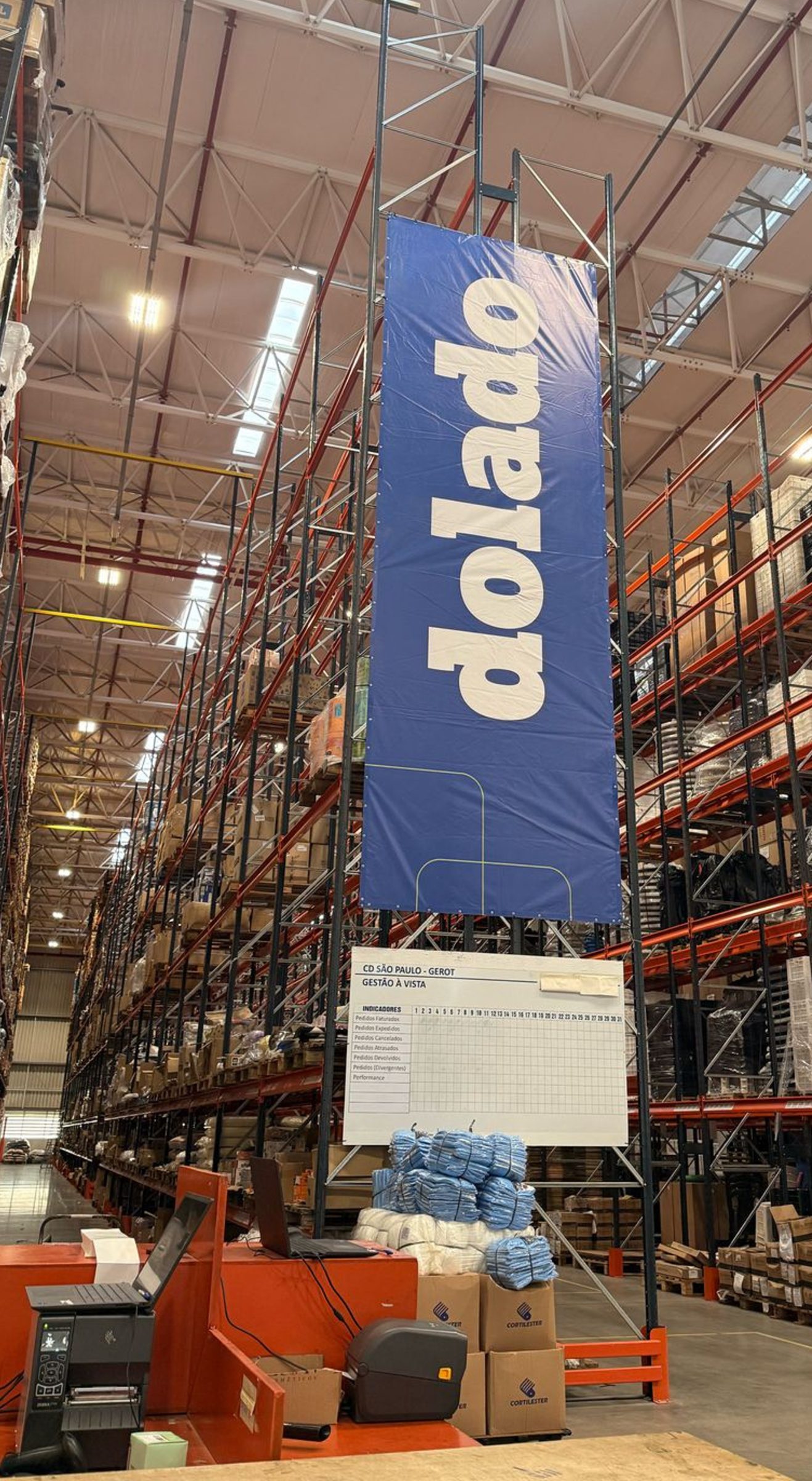 Centro de Distribuição Dolado em Itapevi-SP — banner Dolado pendurado entre corredores de paletes.